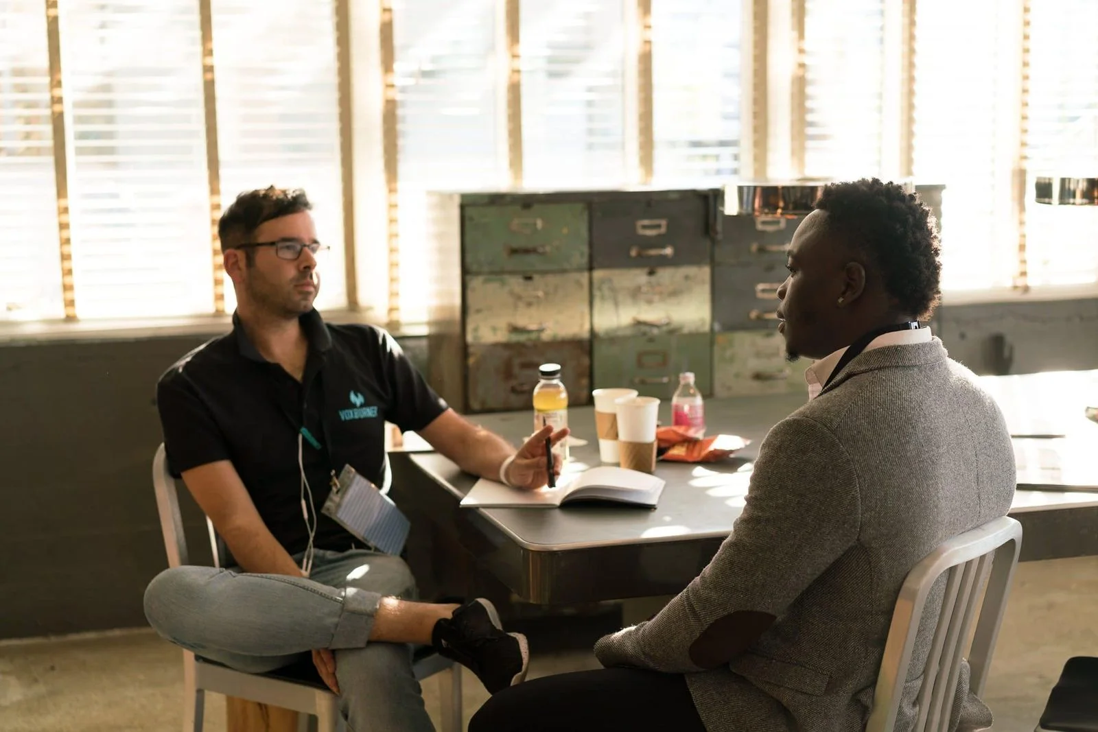 Deux hommes échangent assis à une table lors d’un rendez-vous de recrutement